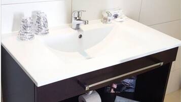 Un baño con un lavabo blanco, un espejo y un perchero para toallas.