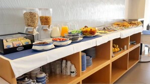 A buffet setup with various food items and beverages, including cereals, fruits, and a juice dispenser.