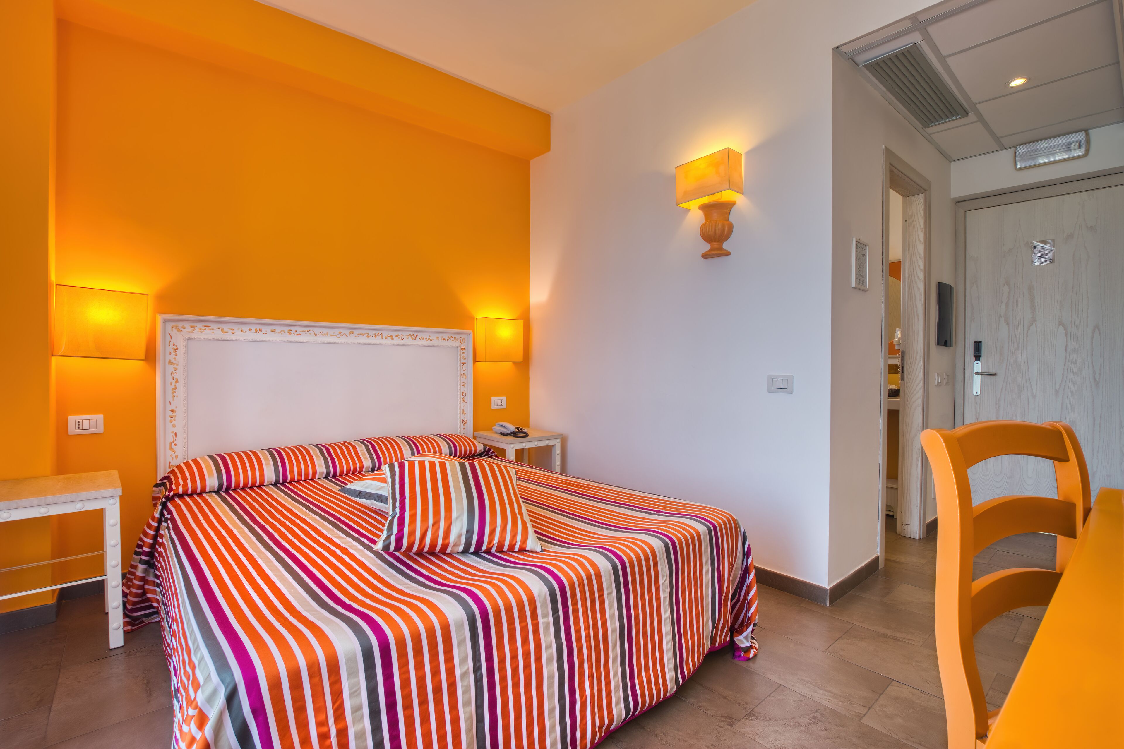 Une chambre d’hôtel avec un grand lit, une table de chevet, une chaise et une porte donnant sur une salle de bain.