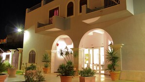 A building with multiple balconies, arched doorways, and potted plants. - Hotel O'scià (Lampedusa)