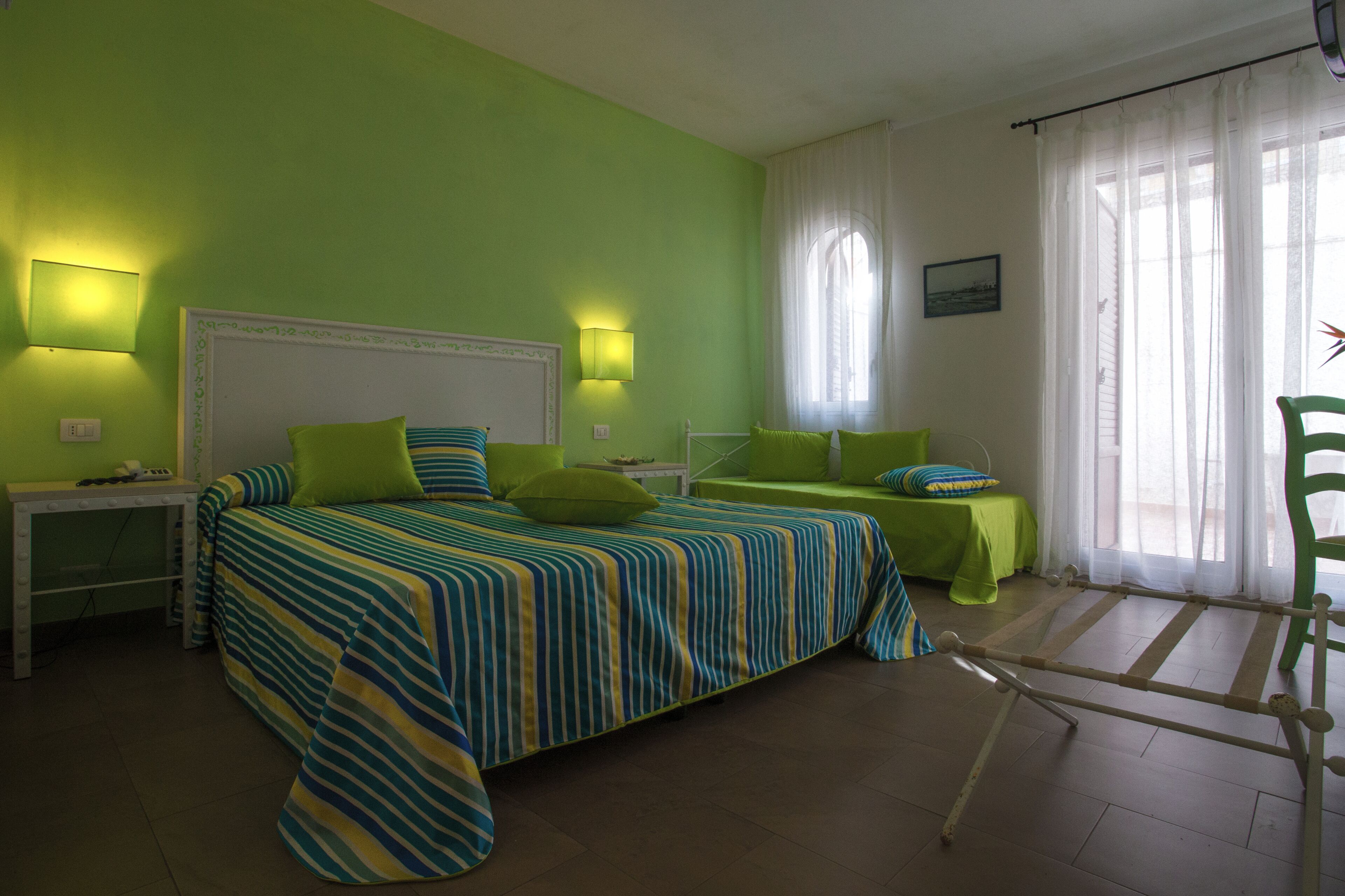 Een kamer met een bed, twee nachtkastjes, een stoel en een raam met gordijnen.
