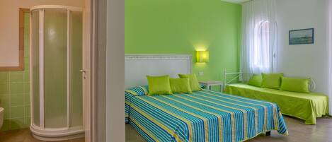A room with a bed, a bedside table, and a shower area.