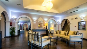 A spacious lobby with a reception desk, seating area with sofas and armchairs, and a large chandelier. - Hotel O'scià (Lampedusa)