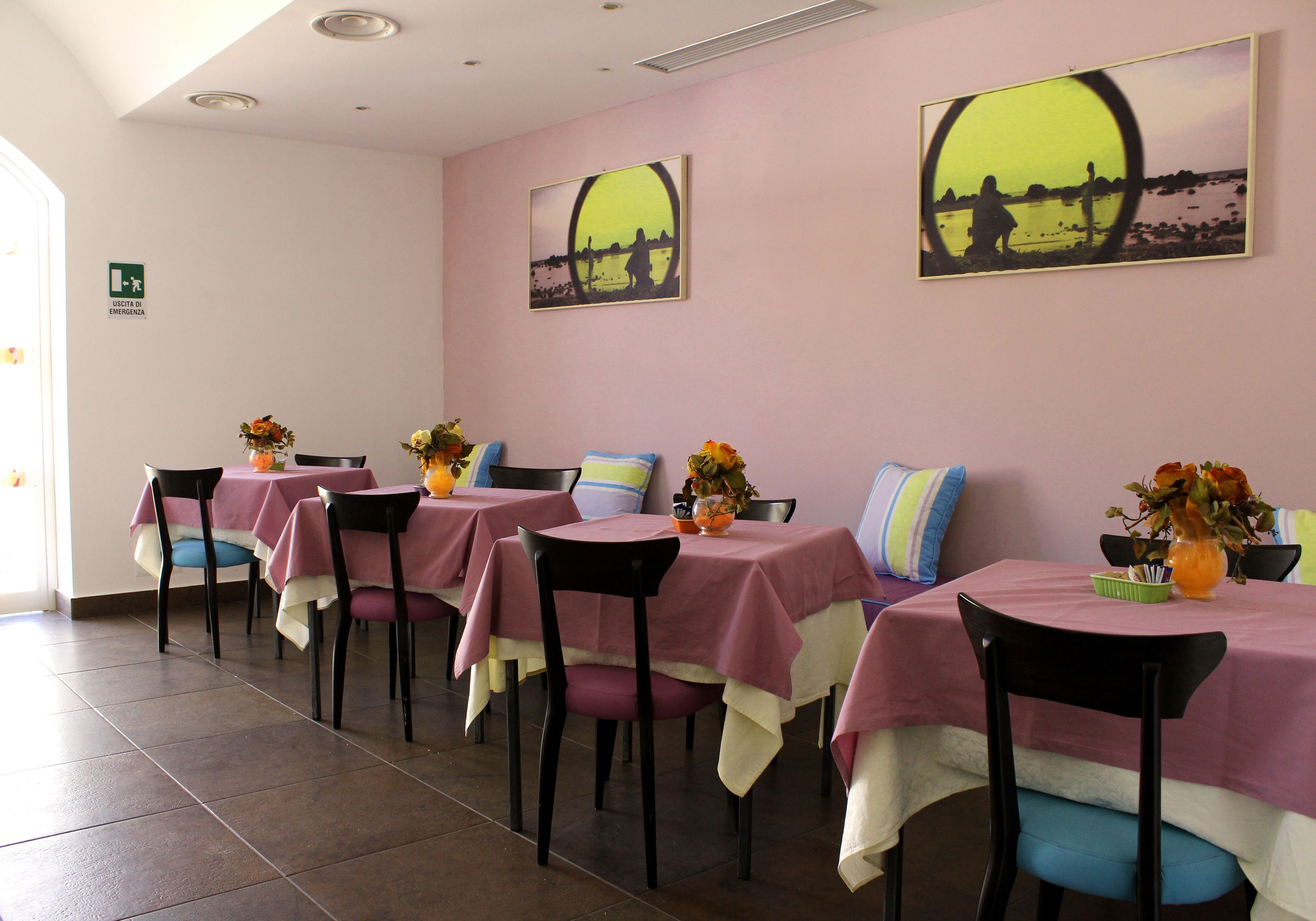 Ein Essbereich mit Tischen für vier Personen, jeder Tisch ist mit einer rosa Tischdecke und einem Blumenstrauß dekoriert.