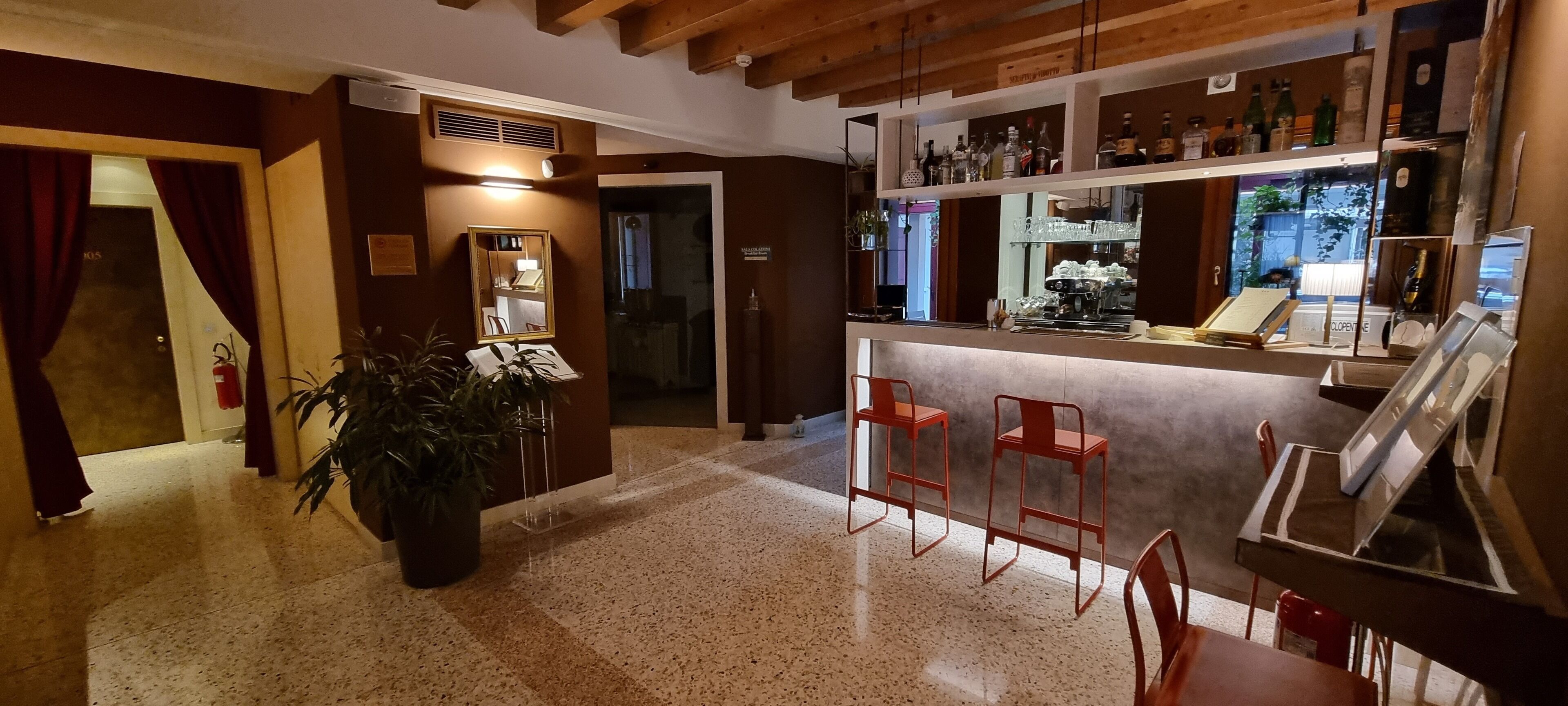 A bar area with stools, a counter, and shelves with bottles.