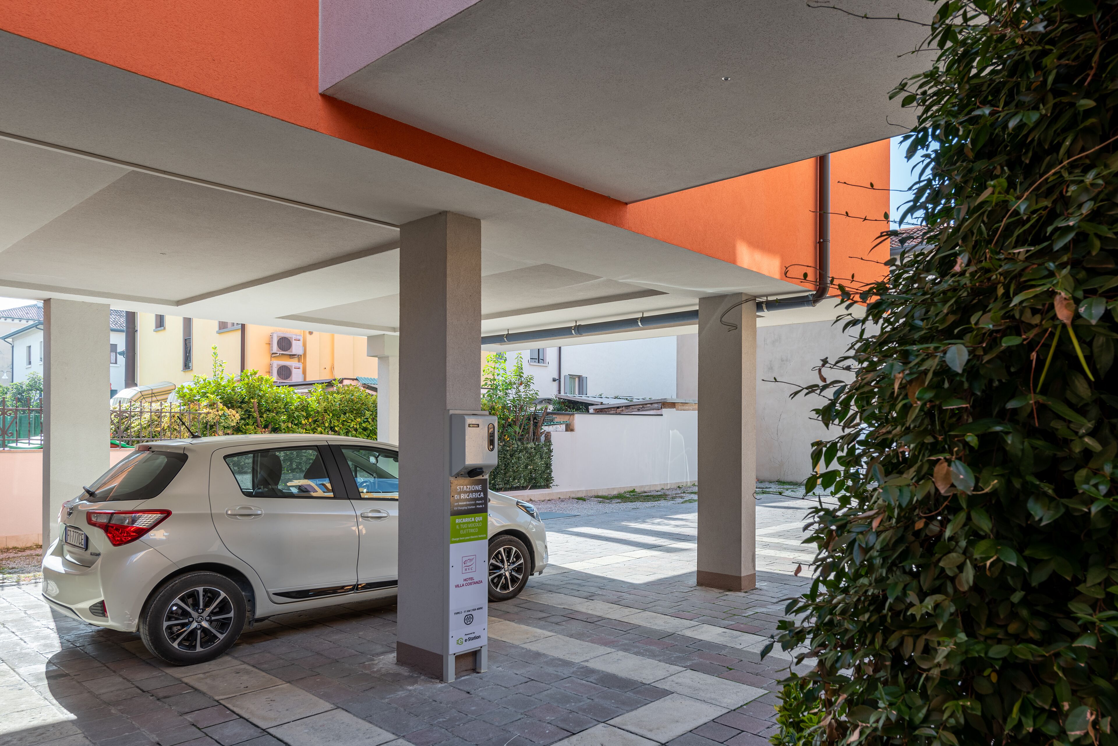Un cotxe blanc estacionat sota una zona coberta amb una estació de càrrega.