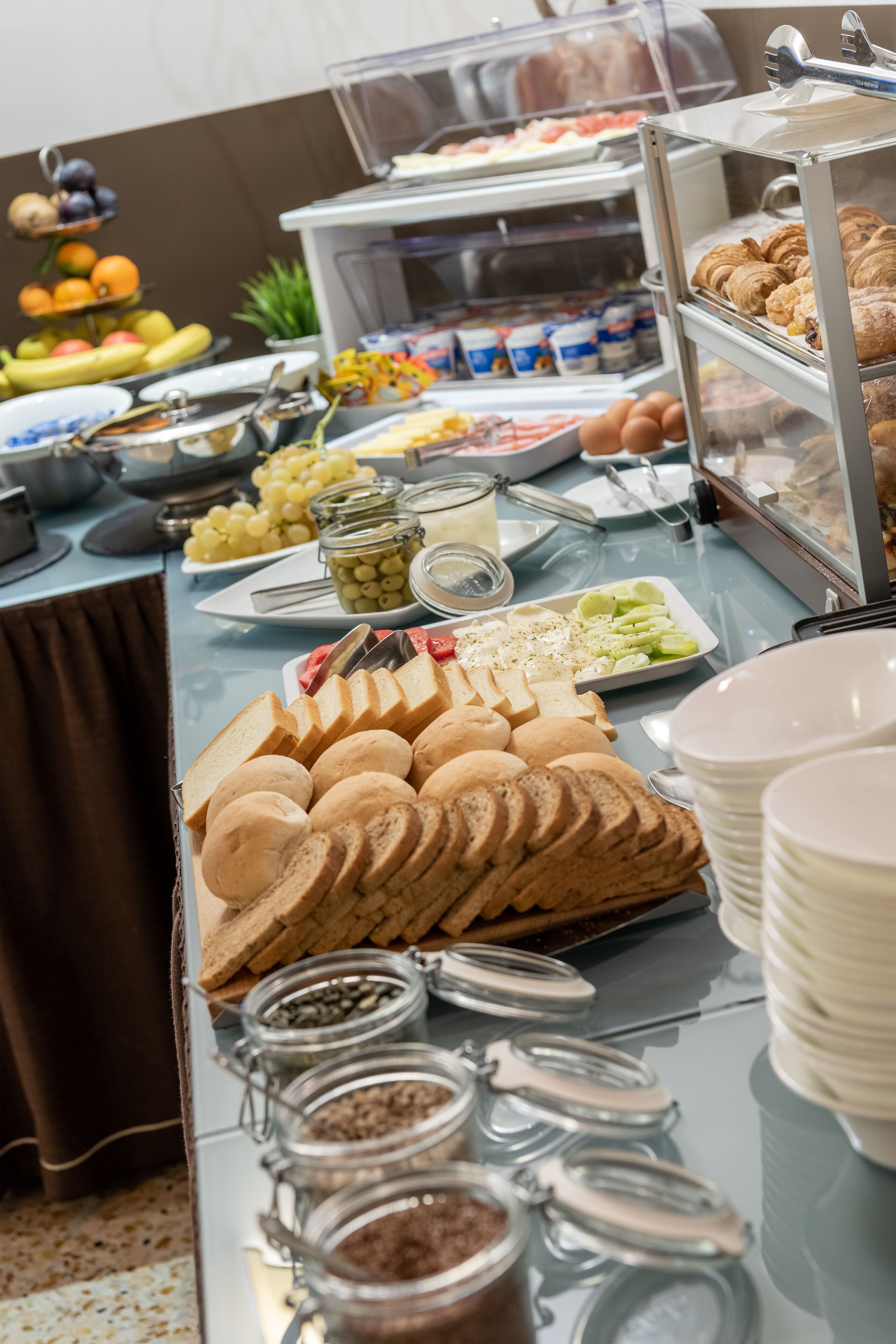 A buffet with various food items including bread, fruits, and condiments.