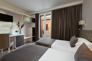 A hotel room with a bed, a desk, a TV, and a view of the outside.