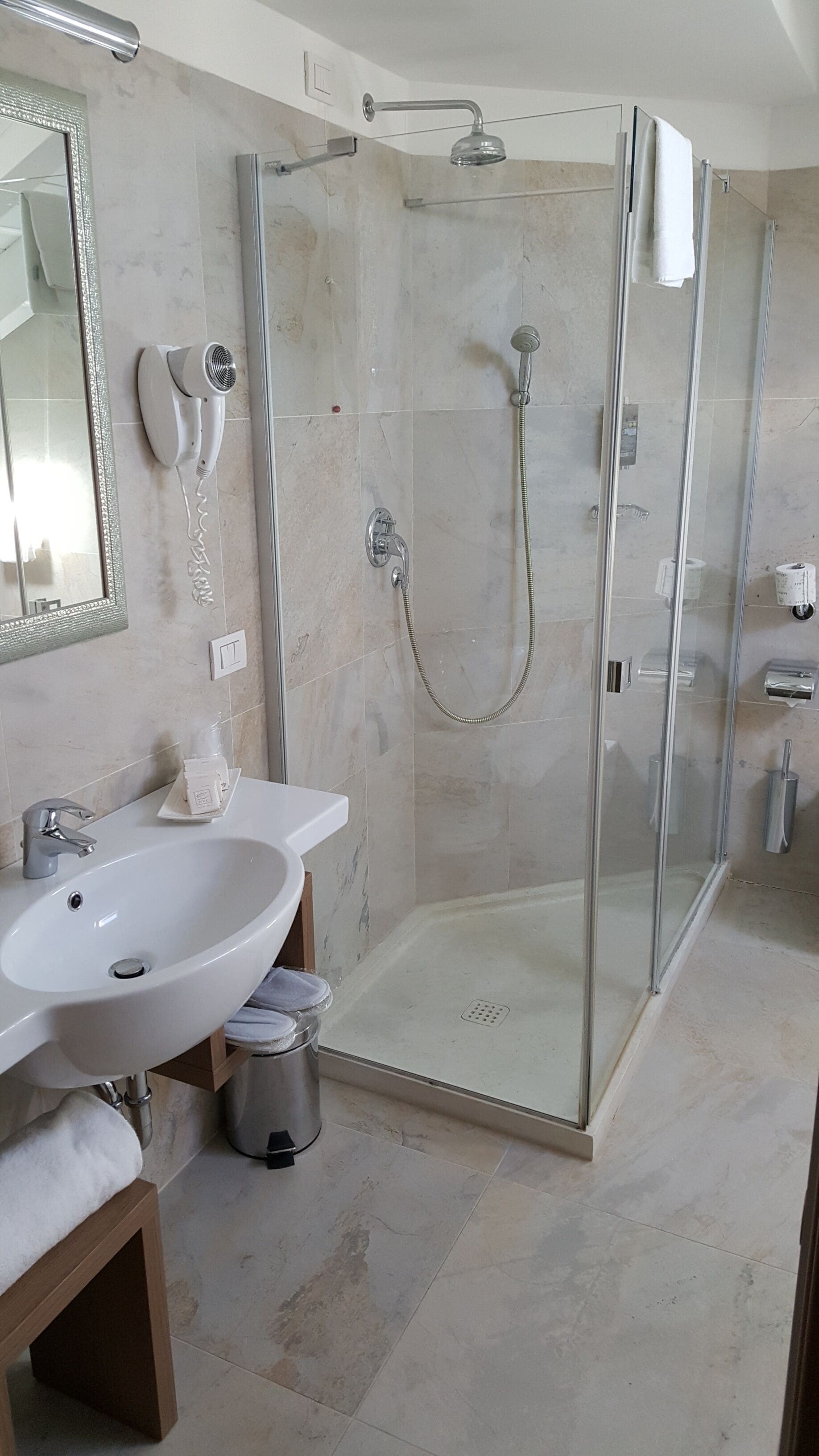 A modern bathroom with a glass-enclosed shower, a white sink, and a mirror.