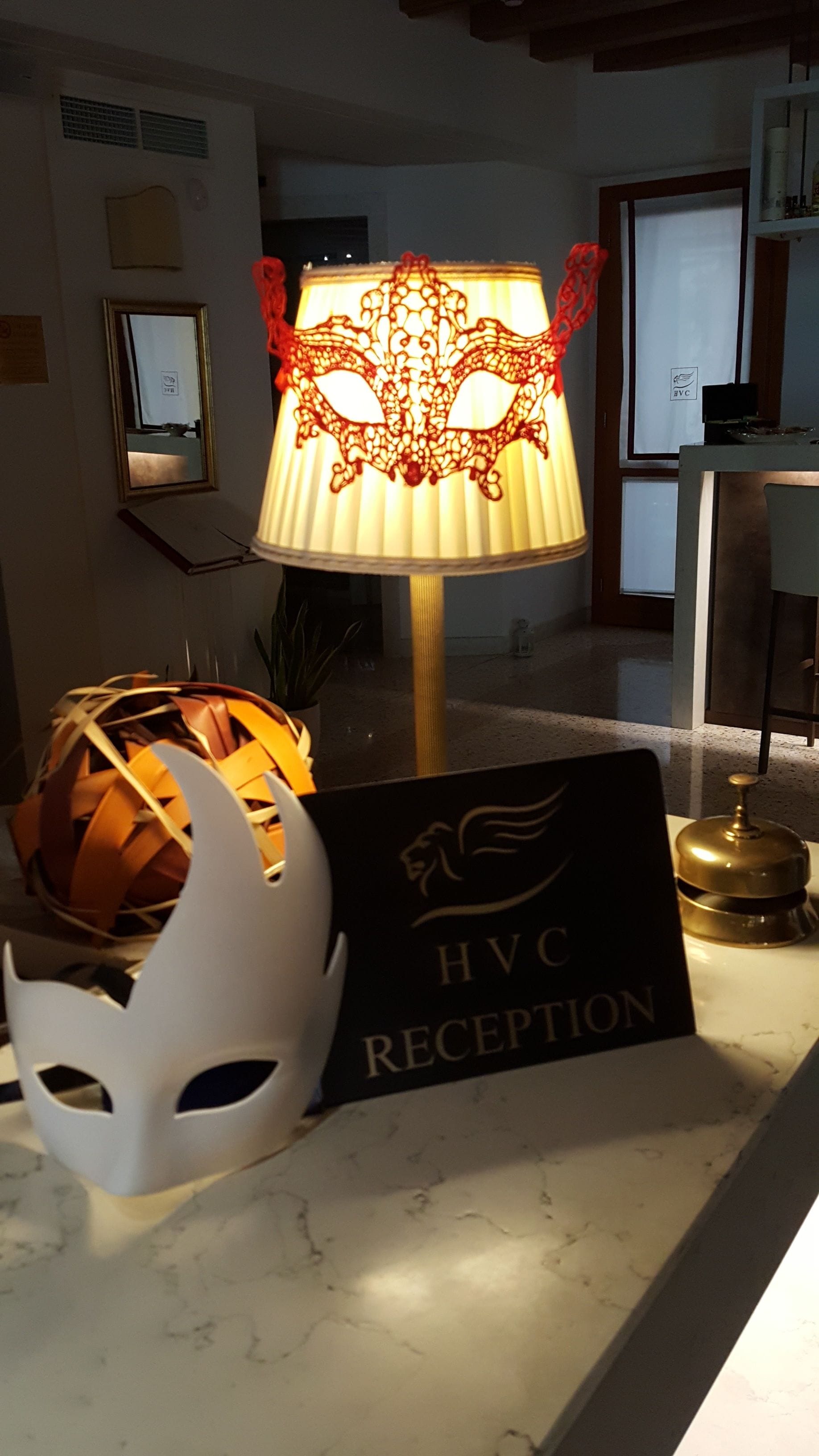 Ein Empfangsbereich mit einer Lampe, einer Maske und einem Schild mit der Aufschrift 'HVC RECEPTION'.