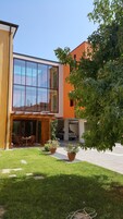 Un edificio moderno con amplios ventanales, un patio cubierto y plantas en macetas.