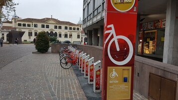 Une station de vélos en libre-service avec des vélos rouges et un panneau rouge orné d’un symbole de vélo blanc.