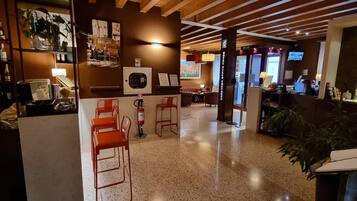 Un vestíbulo de hotel con zona de bar, asientos y mostrador de recepción.