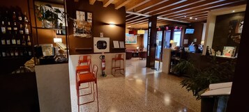 Un vestíbulo de hotel con zona de bar, asientos y mostrador de recepción.