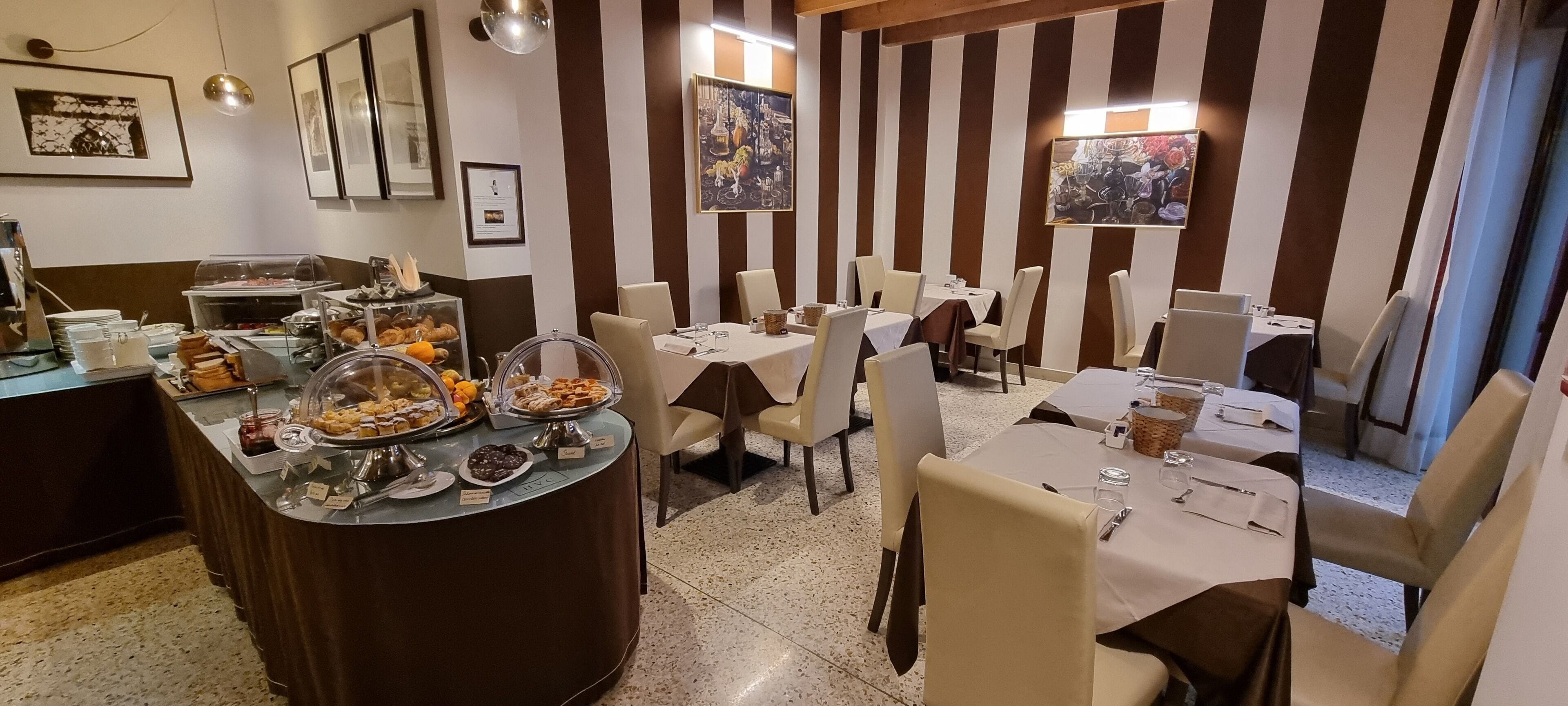 A restaurant with striped walls, round tables, and a buffet area with various food items.