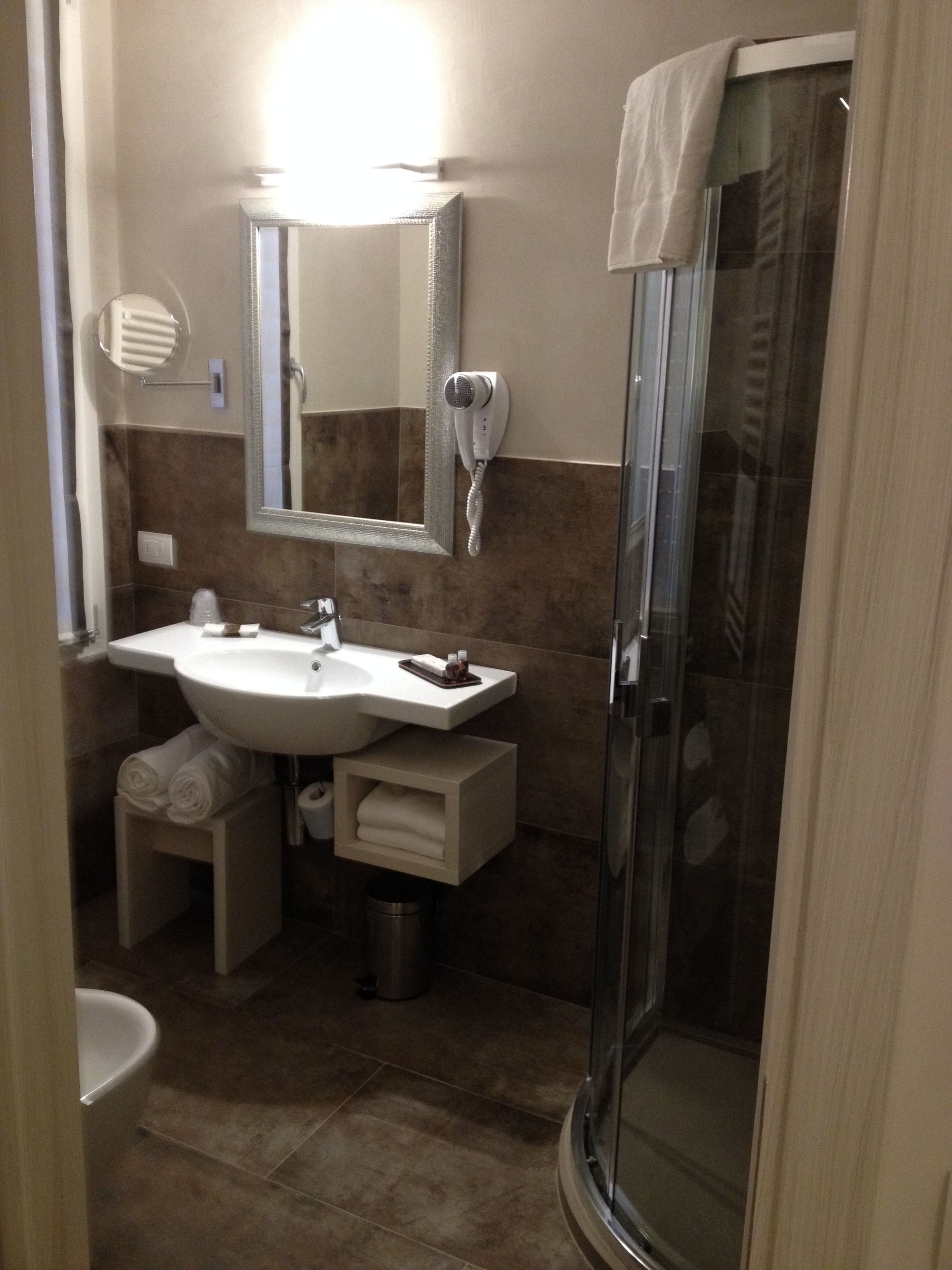 Une salle de bain équipée d’un lavabo, d’un miroir, d’un porte-serviettes et d’une douche à parois de verre.