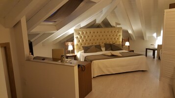 Una camera da letto con un letto grande, una scrivania e una sedia. Si vede una finestra con vista sul cielo.