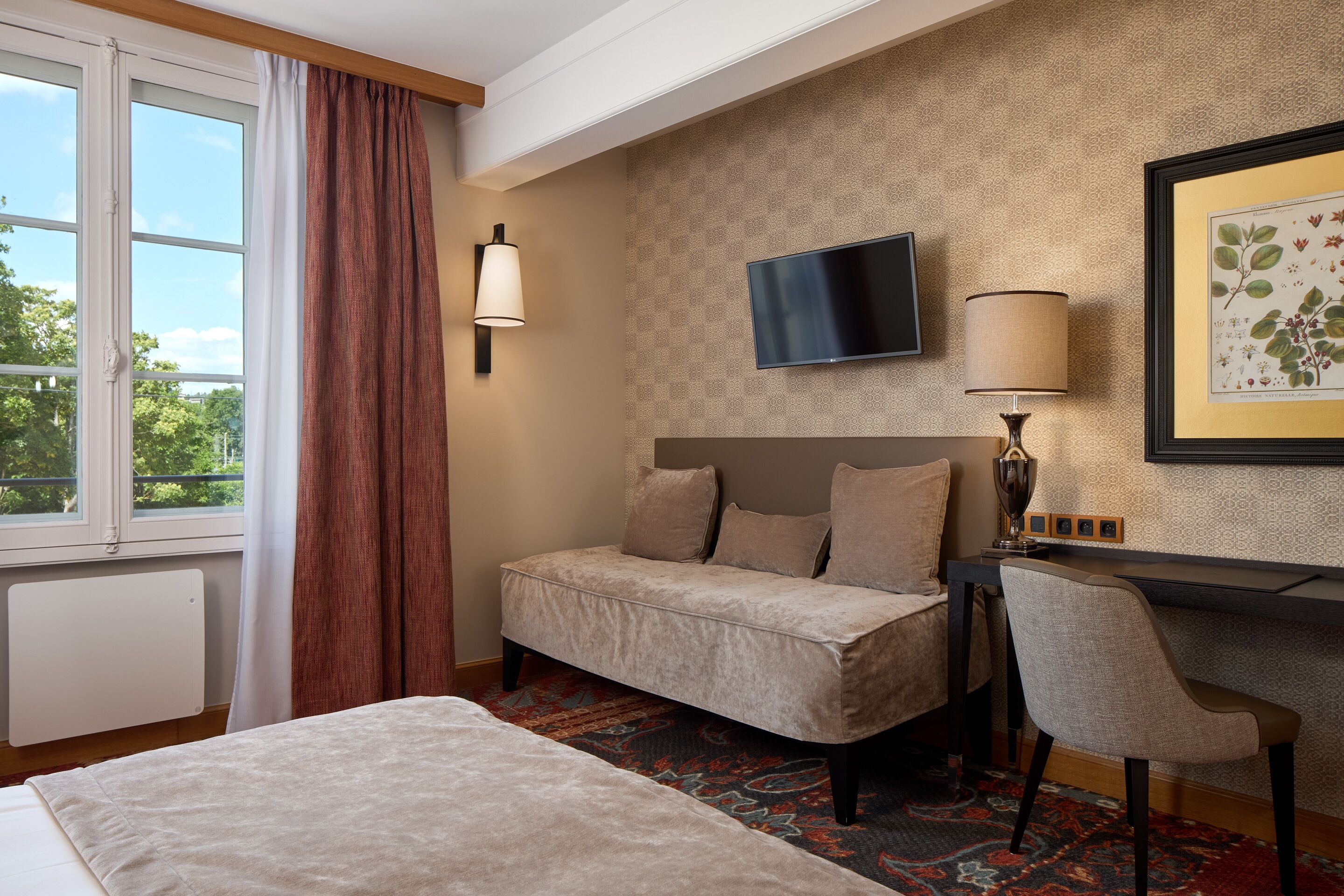 A hotel room with a bed, a desk, a chair, a television, and a window with curtains.