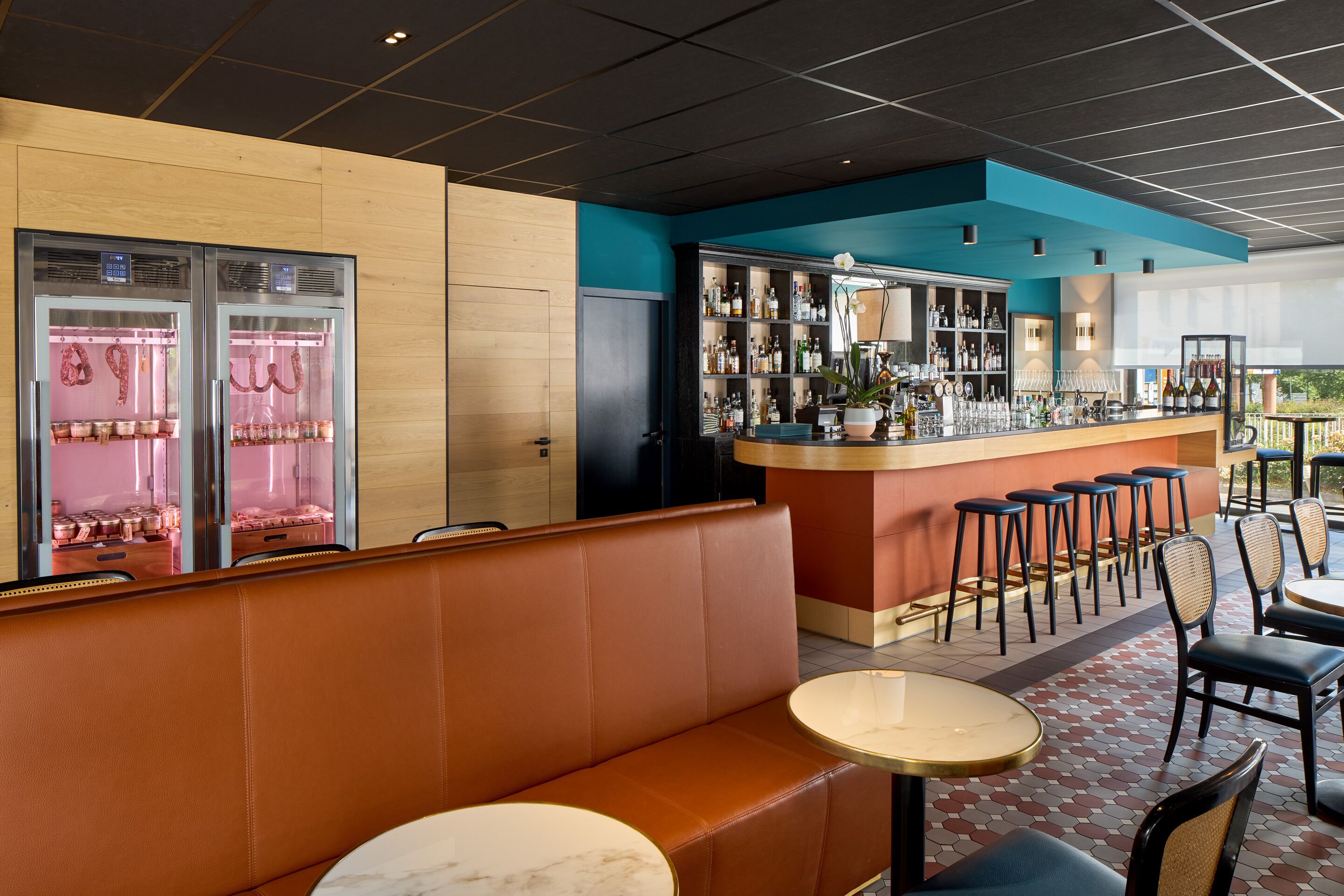 Un restaurante con zona de bar, asientos y una vitrina con alimentos.