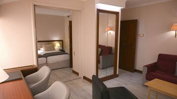 A hotel room with a bed, a desk, a chair, a sofa, and a mirror.