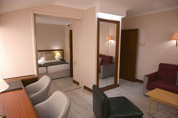 A hotel room with a bed, a desk, a chair, a sofa, and a mirror. - Hôtel Le Rempart (Tournus)