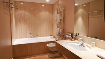 A modern bathroom with a wooden vanity, a double sink, a bidet, and a large mirror.
