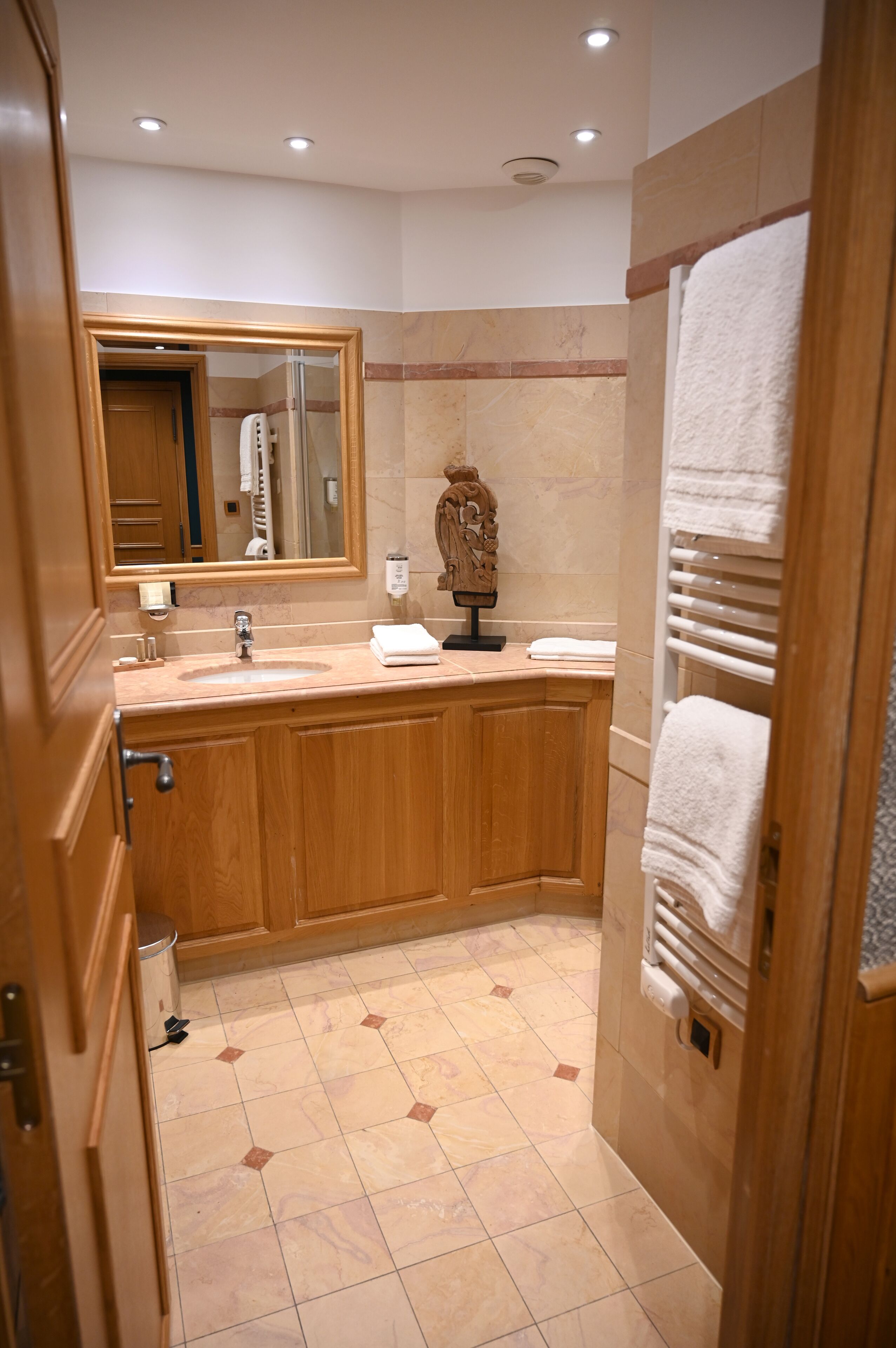 A bathroom with a wooden vanity, a sink, a mirror, and a towel rack.