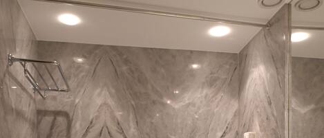 A modern bathroom with a marble wall, a bathtub, a sink, and a mirror.
