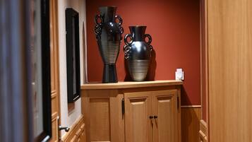 A hallway with wooden cabinets, a patterned carpet, and two large vases on top of a cabinet.