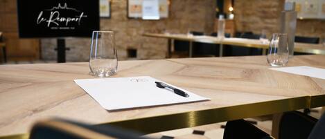 A conference room with a wooden table, two glasses, a pen, and a whiteboard with a logo.