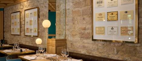 Un restaurante con mesas de madera, sillas azules y certificados enmarcados en la pared.