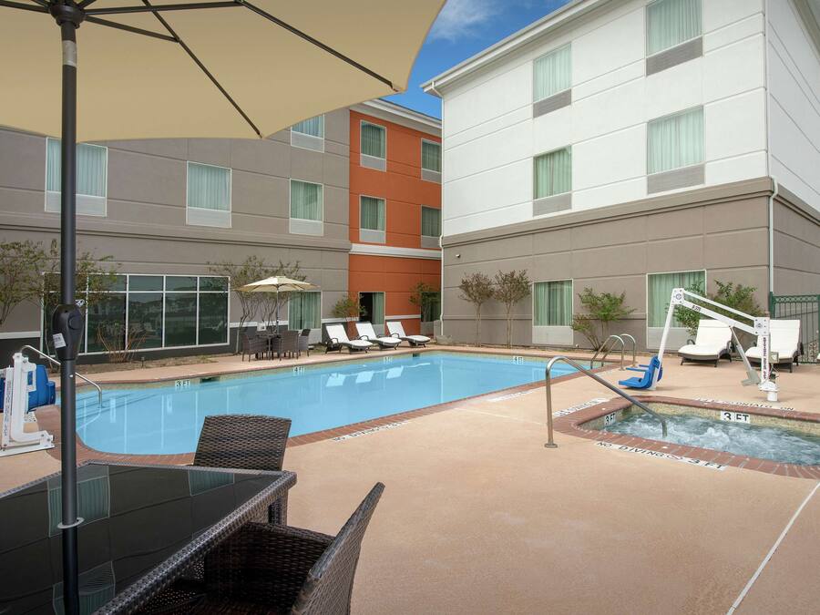A hotel pool area with lounge chairs, a hot tub, and a pool table.