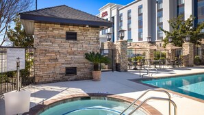 A hotel with a pool, outdoor seating, and a stone building. - Hampton Inn & Suites Manteca (Manteca)