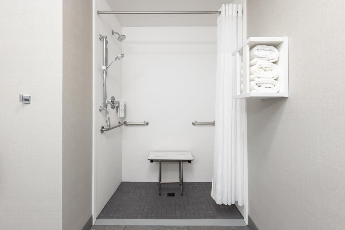 A bathroom with a shower, a towel rack, and a small table.