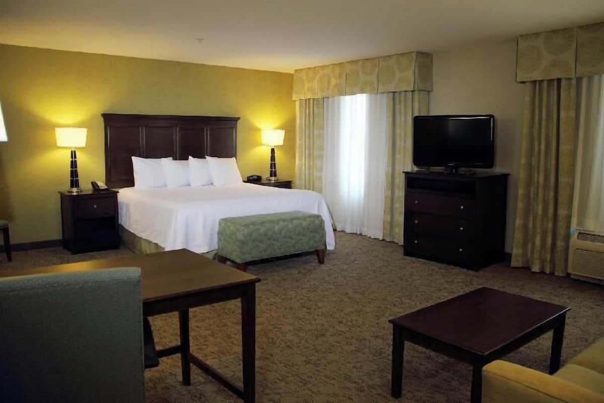 A hotel room with a bed, bedside tables, a television, a desk, and a chair.