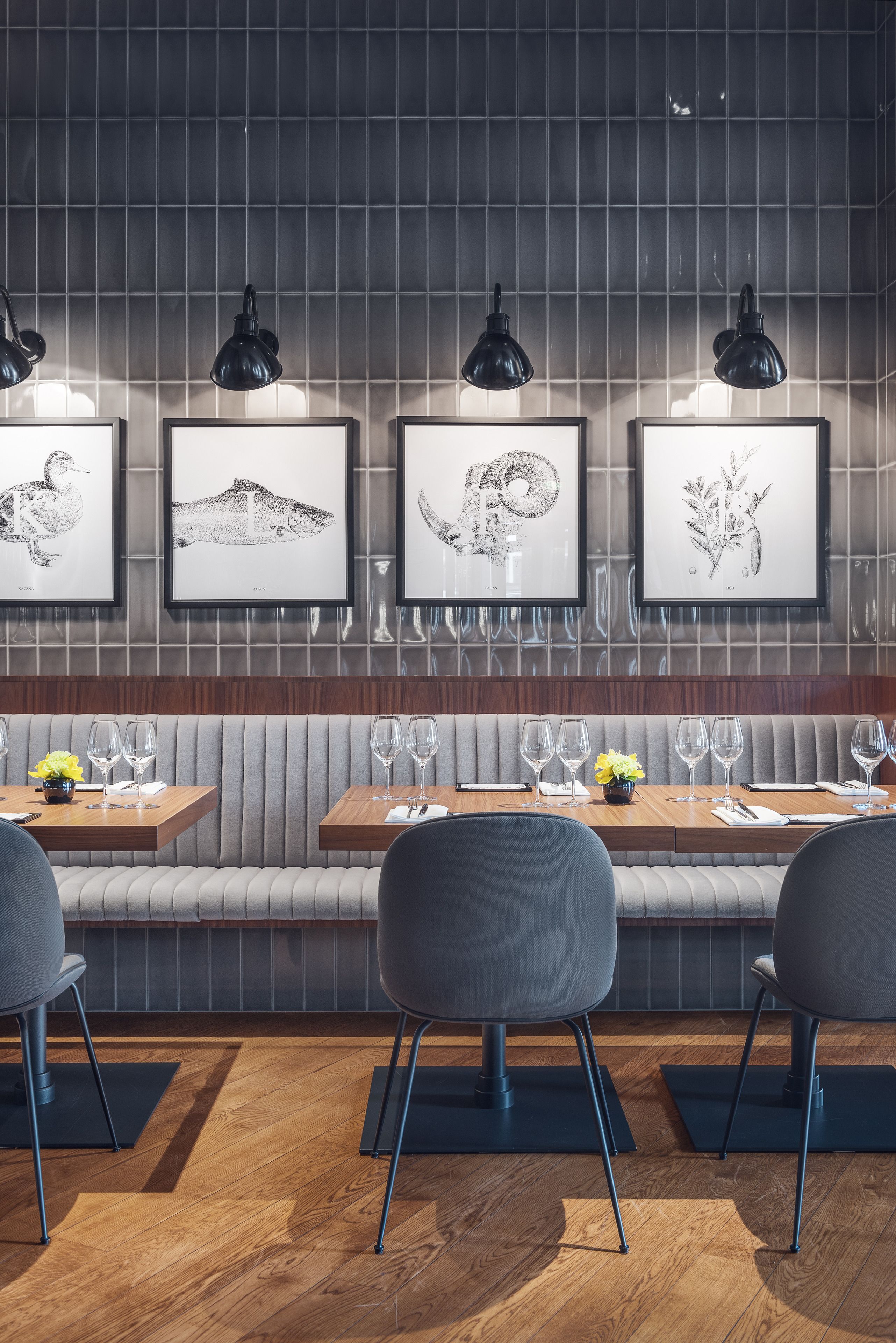 Un restaurante con una larga zona de asientos tipo banco, obras de arte enmarcadas en la pared e iluminación moderna.