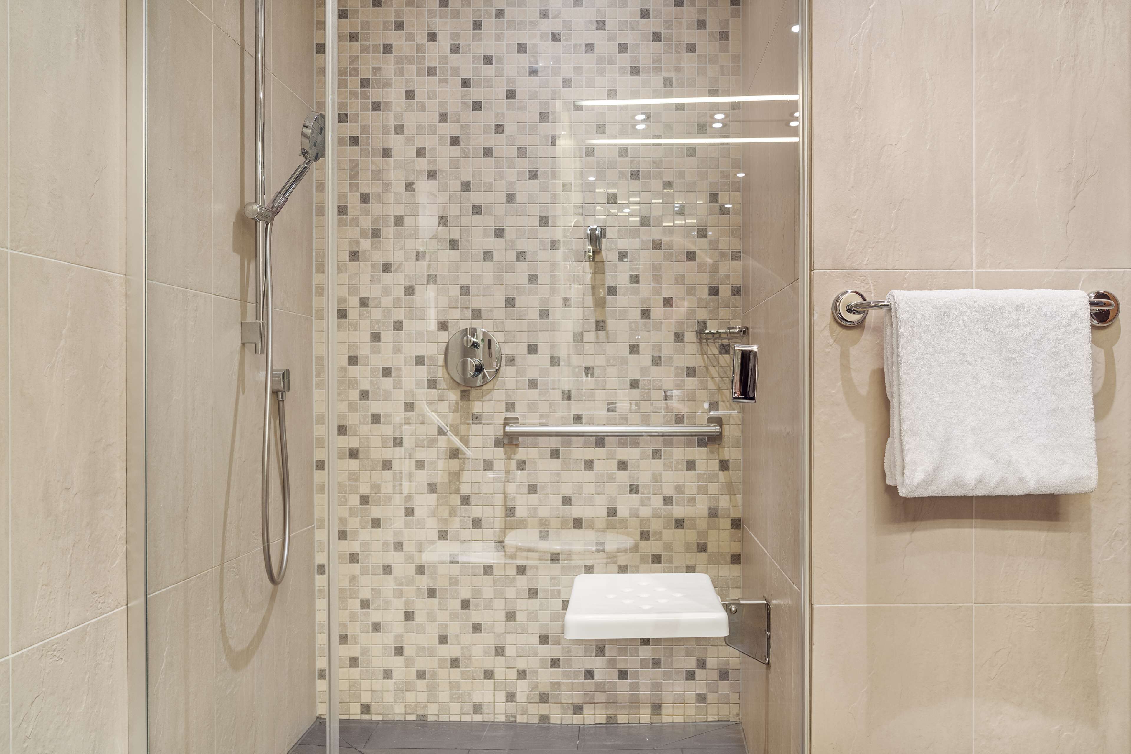 Un baño moderno con cabina de ducha de vidrio, inodoro y perchero.