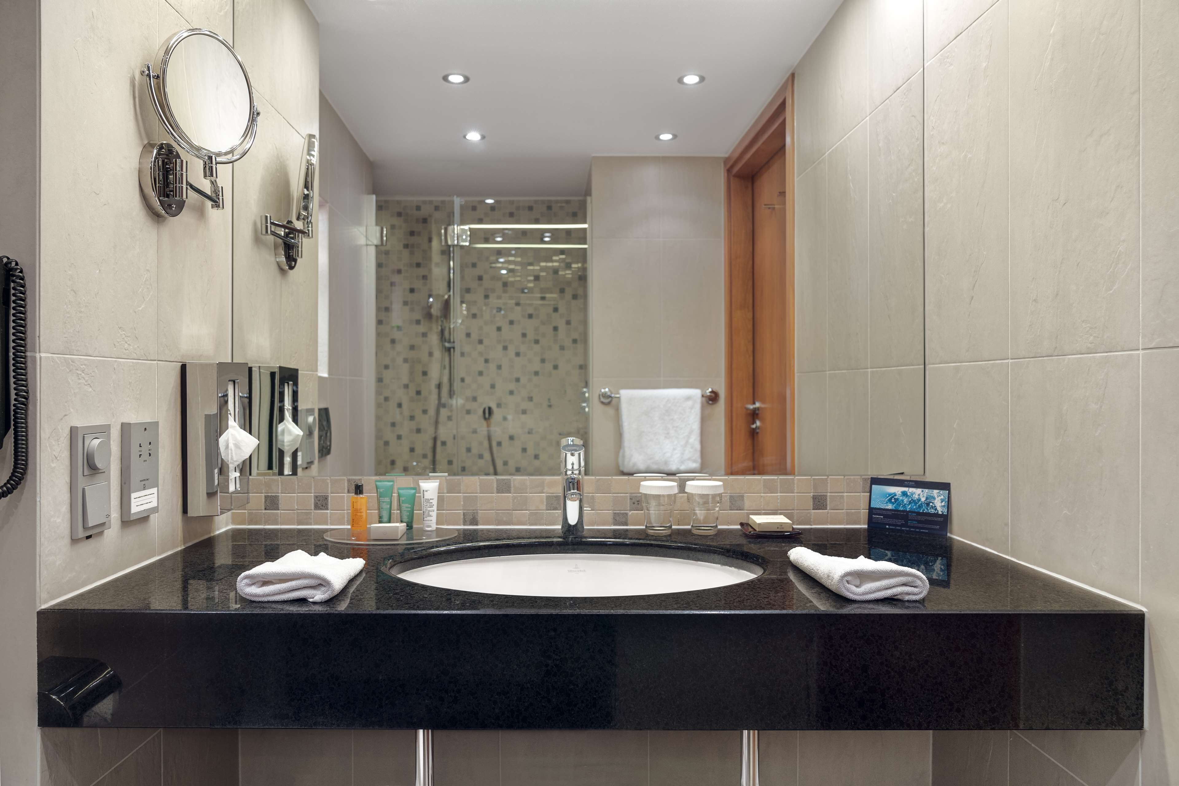 A modern bathroom with a large sink, a mirror, and a glass shower enclosure.