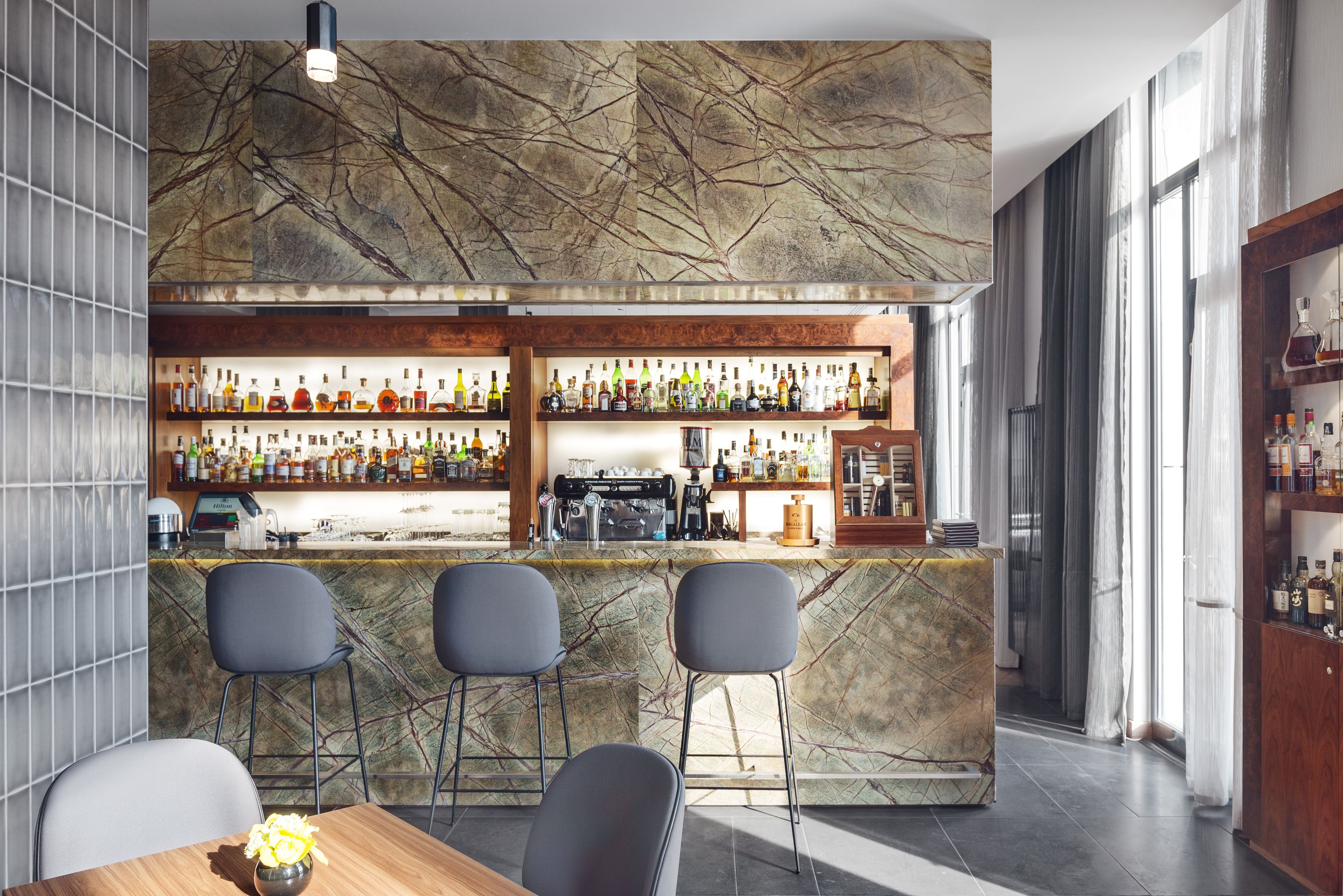 A bar area with a marble countertop, multiple shelves of bottles, and bar stools.