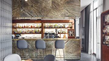 A bar area with a marble countertop, multiple shelves of bottles, and bar stools.