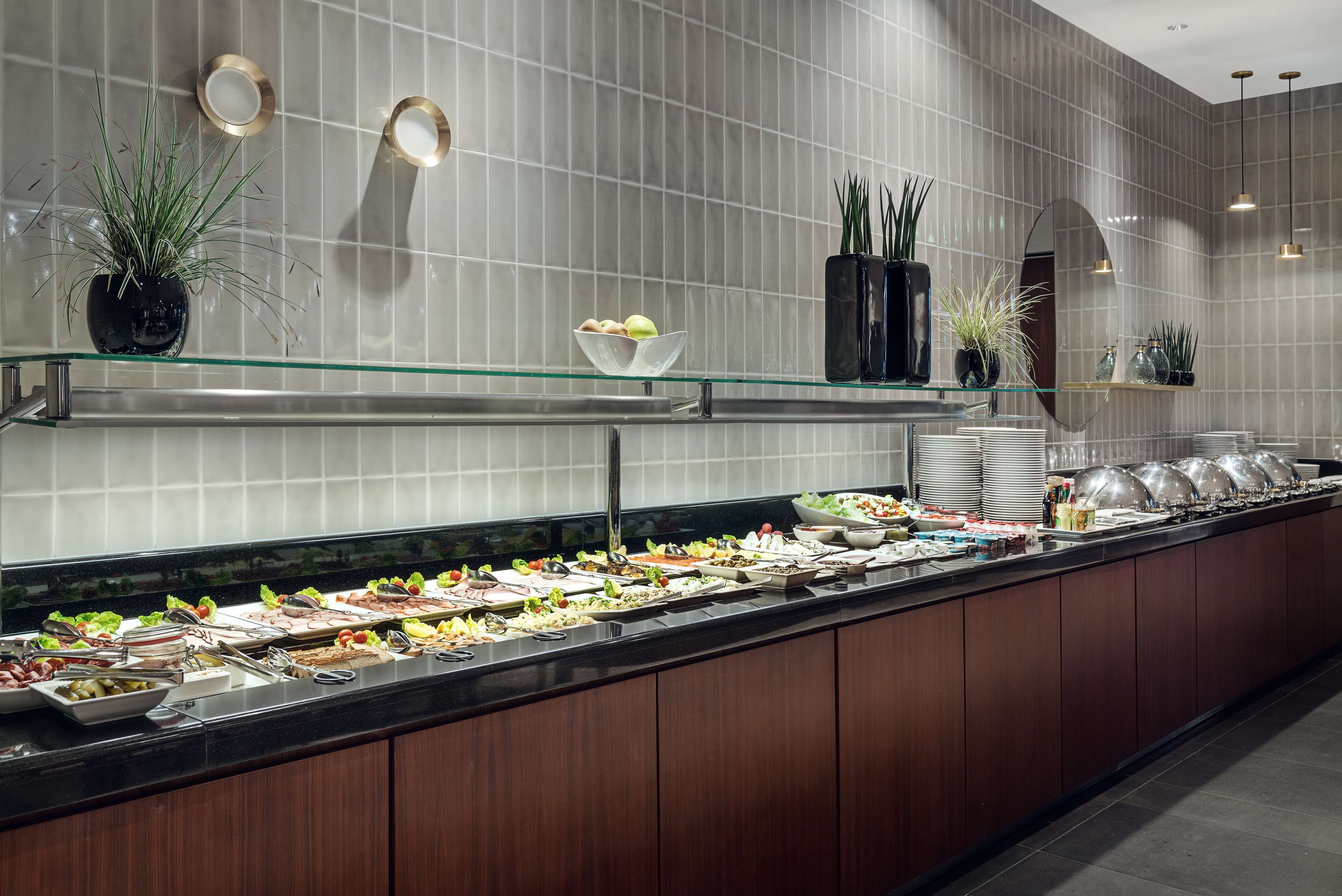 A buffet with various food items and decorative plants.