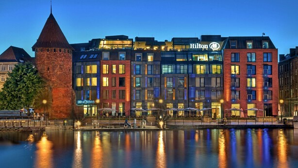 A hotel with a modern design, featuring a prominent tower and a mix of brick and glass facades.