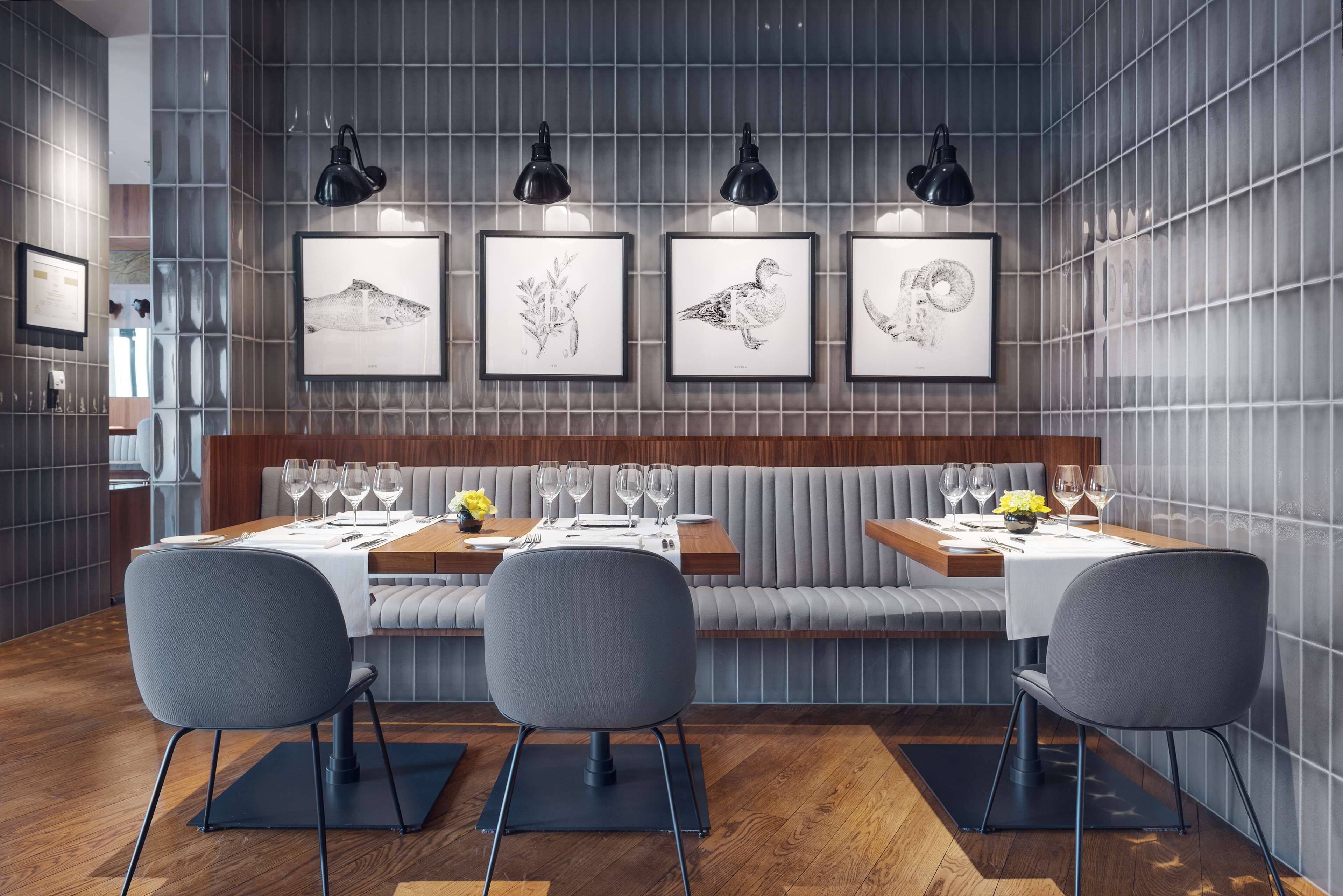 A modern dining area with a wooden table set for four, grey upholstered chairs, and a bench seating area.
