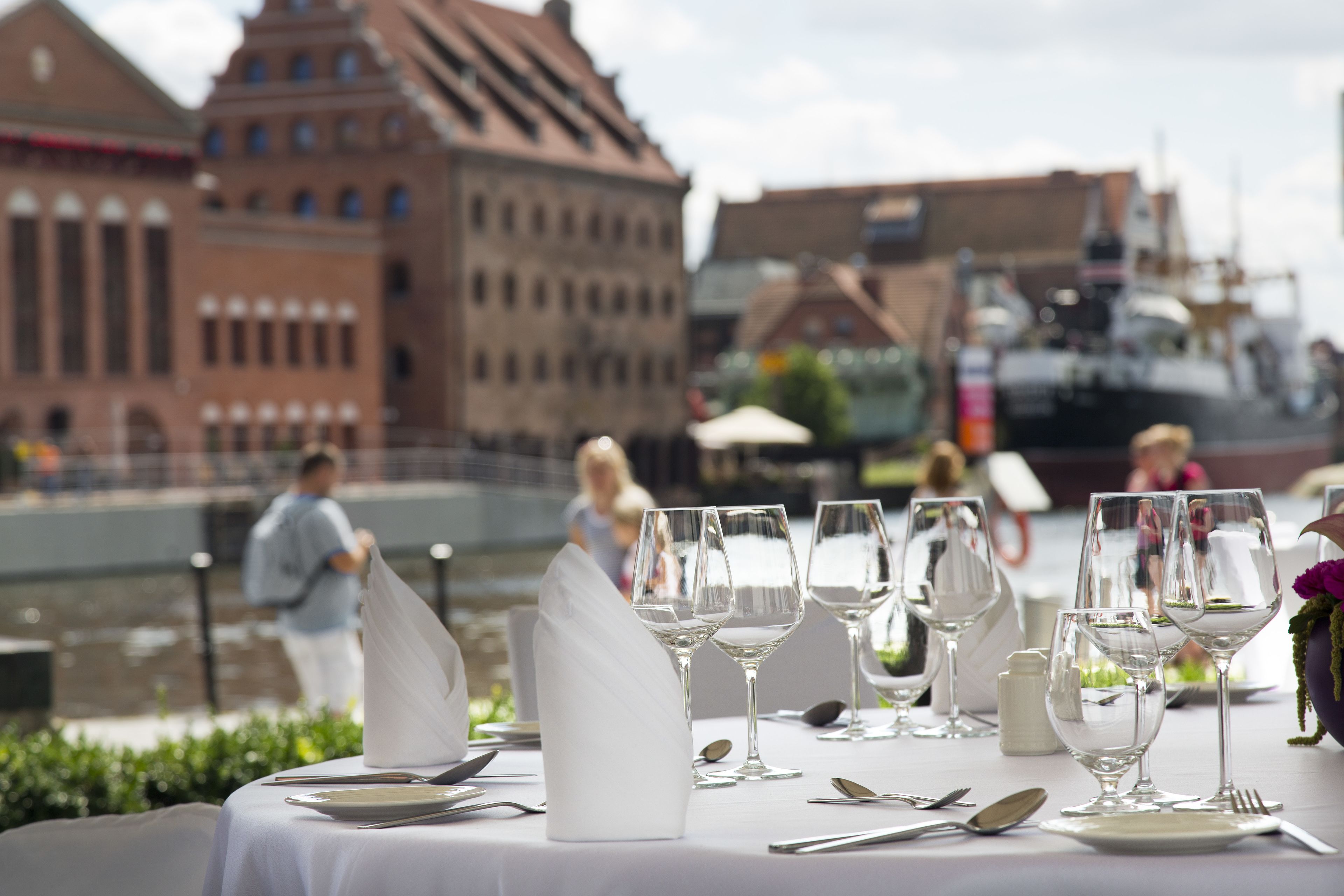 A table set for a meal with a view of a historic building and a boat in the background.