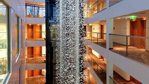 A multi-level atrium with a central decorative light fixture, glass railings, and patterned carpeted floors.