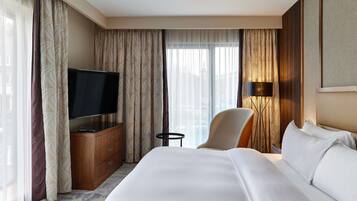 A hotel room with a bed, a TV on a wooden cabinet, a chair, and a lamp.