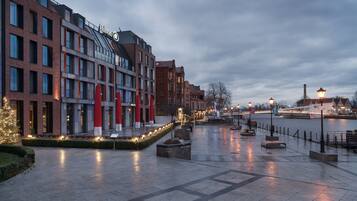 A modern hotel with a brick facade, a glass entrance, and a waterfront view.