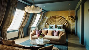 A modern bedroom with a curved headboard, a sofa, and a coffee table with a vase of flowers.