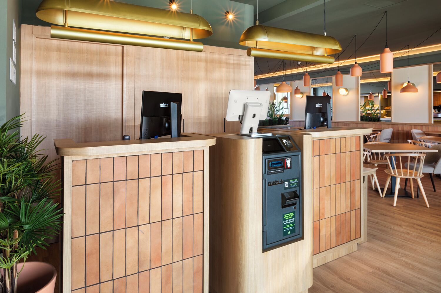 A modern reception area with a wooden counter, a cash machine, and pendant lighting.