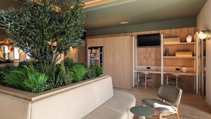 A modern living room with a sofa, two chairs, a small table, a TV, and a wooden cabinet with shelves. - B&B Hotel Granada (Pulianas)